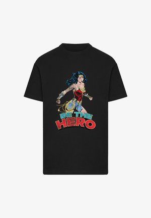 Schwarzes Baumwoll-T-Shirt mit einem Grafikmotiv von Wonder Woman in Aktion, mit dem Text "SEI DER HELD" in fetten roten und blauen Buchstaben.
