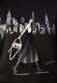 Peça preta com uma ilustração na moda. Modelo usa uma camisa branca da DKNY, saia de tule em camadas e botas robustas, segurando uma carteira de contas.