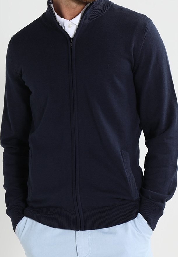 Marinblå zip-up kofta, stickat tyg, ribbat krage och ärmslut, två sidofickor, slät yta, figursydd design, inga synliga mönster.