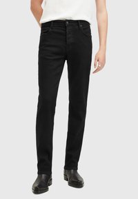Jeans de mezclilla negra con un ajuste slim, cinco bolsillos y cierre de botones. Textura suave, diseño clásico y sin patrones visibles.