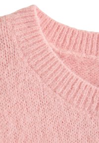 Blød lyserød strikket sweater med ribbet rund halsudskæring og tæt tekstureret garn, close-up.