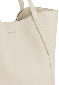 Beige leren tote bag met een gestructureerd oppervlak, een brede open bovenkant en een lange verstelbare schouderriem met metalen hardware.
