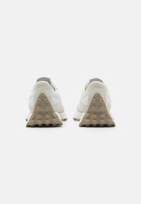 Zapatillas blancas con una suela de goma beige texturizada y un diseño de tacón triangular. Materiales superiores de cuero liso y ante crean un aspecto elegante.