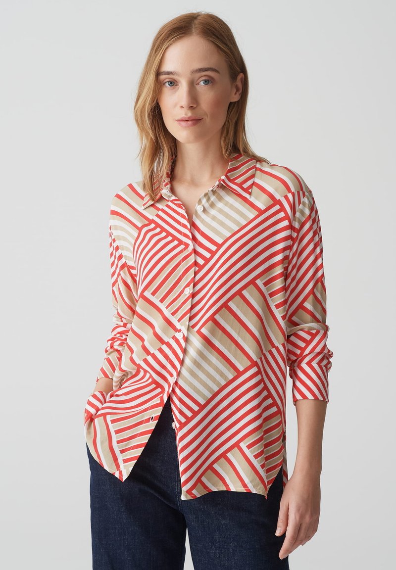 Camicia con bottoni caratterizzata da un motivo geometrico di strisce diagonali rosse, beige e oro su uno sfondo chiaro. Maniche lunghe, vestibilità morbida.