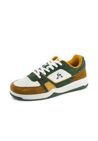 Sneaker in suede verde e marrone con dettagli bianchi, punta tonda, rivestimento giallo a contrasto, design perforato e dettaglio del logo sul lato.