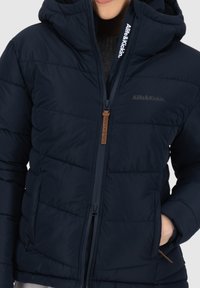 Giubbotto imbottito blu navy con cappuccio, texture trapuntata, chiusura anteriore con zip e dettagli con logo sulla zip e all'interno del colletto.
