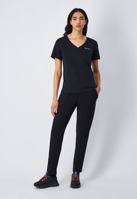 Zwarte katoenen V-hals T-shirt gecombineerd met zwarte joggingbroek. De outfit heeft een eenvoudig ontwerp met minimale accenten en een comfortabele pasvorm.