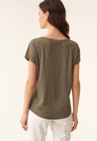 Oliven grøn løs pasform t-shirt med korte ærmer, rund halsudskæring og en buet kant. Fremstillet af blødt, letvægtsstof med subtil tekstur.