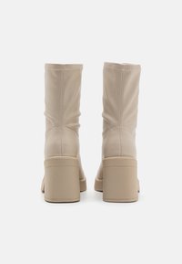 Beige Leder Stiefeletten mit einem lässigen Design, ausgestattet mit einem breiten Blockabsatz und sichtbaren Steppnähten auf der Rückseite.