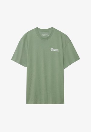 Groene T-shirt met korte mouwen en een ronde hals. Beschikt over witte tekst "AMSTERDAM Bloemenmarkt" en bloemenillustraties op de linkerkant van de borst.