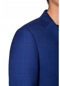 Niebieski marynarka z wzorem w kratę, o strukturalnym fasonie, wyrazistych klapach i teksturowanej tkaninie. Widoczne detale przeszycia na kołnierzu.