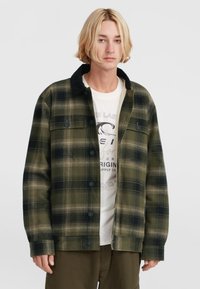 Groene en zwarte geruite shirtjack met een zwarte kraag, voorzien van knopen en twee borstzakken, gedragen over een wit graphic t-shirt.