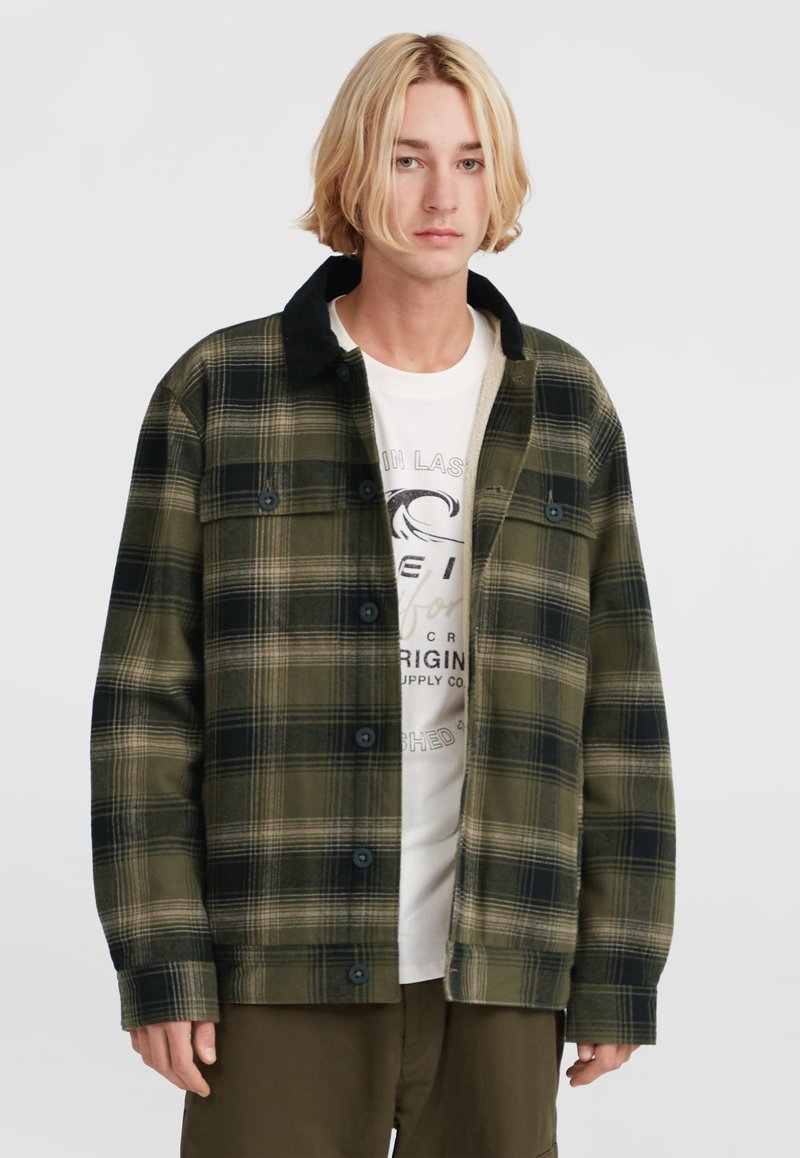 Groene en zwarte geruite shirtjack met een zwarte kraag, voorzien van knopen en twee borstzakken, gedragen over een wit graphic t-shirt.