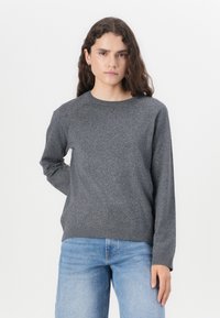 Grå genser med rund hals laget av et mykt stoff, med lange ermer og en subtil tekstur, sammen med lyseblå jeans.