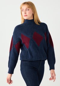 Maglione blu navy lavorato a maglia con collo alto, caratterizzato da motivi a diamante color amaranto e trecce strutturate sul corpo e sulle maniche.