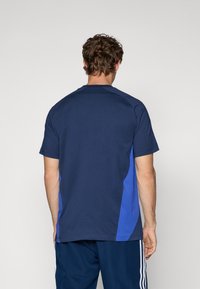 Marineblauwe t-shirt met lichtblauwe zijpanelen. Heeft korte mouwen en een ronde hals. Gemaakt van zachte, lichte stof.