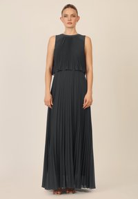 Plissé donkergrijze midi-jurk met een hoge halslijn en gelaagd ontwerp. Soepel, vloeiend materiaal met een getailleerde taille en A-lijn rok.
