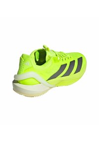 Scarpa sportiva di un luminoso giallo neon con accenti neri, tessuto testurizzato e una suola robusta caratterizzata da un motivo del battistrada distintivo.