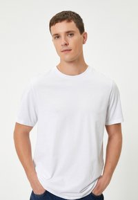 Hvid bomuld t-shirt med korte ærmer og rund hals, der har en afslappet pasform og glat tekstur. Simpelt, ensfarvet design uden mønstre.