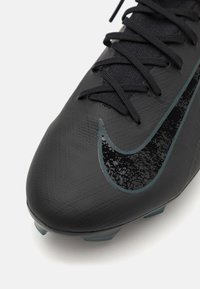 Scarpino da calcio nero con tomaia testurizzata, area dei lacci prominente e un grande logo swoosh nero lucido. Tacchetti moldati sulla suola per una migliore aderenza.