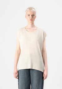 Beige, rövid ujjú póló, kerek nyakkal, puha, texturált anyagból készült. A póló lazán illeszkedik, magas derékú farmernadrággal párosítva.