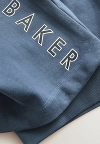 Modrý bavlněný svetr s nápisem "BAKER" v tučném bílém písmu. Měkká textura s žebrovanými manžetami a lemem.