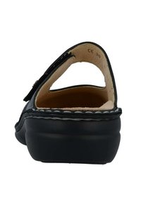 Zwarte leren sandaal met een open achterkant, ronde neus en stiksels rond de zool. Interieur is voorzien van een zachte beige voering.