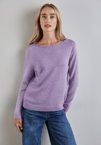 Maglione lavanda con scollatura ampia e maniche lunghe; realizzato in un materiale morbido con orlo e polsini a costine; abbinato a jeans in denim blu.