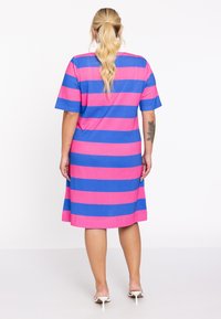 Korte mouw, knielang jurkje met gedurfde roze en blauwe horizontale strepen. Gemaakt van een zachte, rekbare stof met een relaxte pasvorm.
