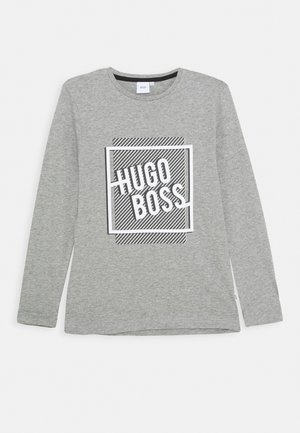 Grå langærmet crew neck-shirt med "HUGO BOSS" i hvide blokbogstaver inde i et sort-hvidt stribet rektangulært design.