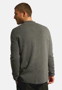 Šedý pletený svetr s rovnými liniemi, dlouhými rukávy a zaobleným spodním lemem. Obsahuje jemnou texturu a minimální švy na zadní straně.