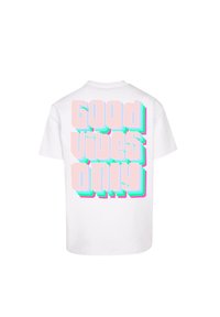 Hvid bomulds t-shirt med en farverig grafik på ryggen, der har teksten "Good Vibes Only" i legende, 3D-stil bogstaver.