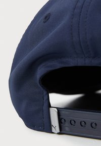 Casquette de baseball bleu marine avec une visière incurvée, texture en tissu, détails de couture subtils et sangle réglable en plastique avec un accent en logo argenté.
