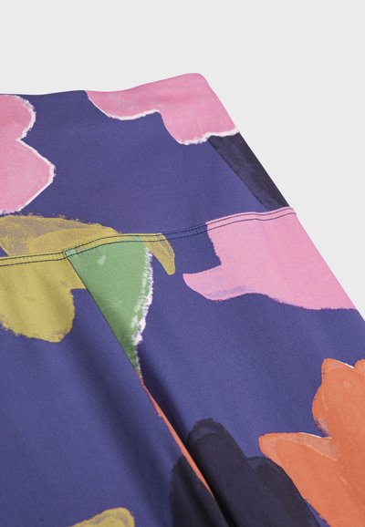 Gros plan sur un tissu à motif floral abstrait en rose, orange, jaune, vert et bleu marine, montrant des coutures détaillées sur un matériau lisse.