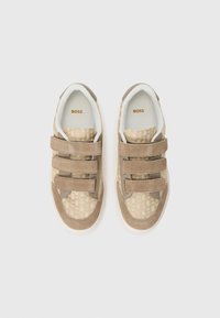 Sneaker beige con strap in Velcro, tomaia in suede e tessuto testurizzato, suola in gomma e fodera interna morbida. Logo del marchio visibile all'interno.