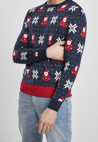 Granatowy sweter z wzorami Świętego Mikołaja i płatków śniegu, wykonany z dzianiny. Posiada czerwony ściągacz u dołu i na mankietach oraz okrągły dekolt.