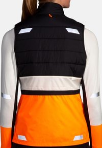 Black and orange athletic vest with reflective accents, quilted texture on upper back, smooth lower section, and zip closure at neck.