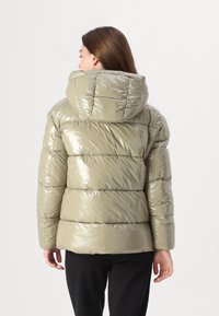 Casaco verde-azeitona volumoso com um acabamento brilhante, apresentando um capuz grande e um design acolchoado horizontal. Silhueta simples e elegante.