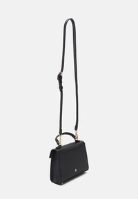 Sac à main en cuir noir avec une forme structurée, une poignée supérieure et une bandoulière réglable. Présente des ferrures en métal doré et une finition texturée.