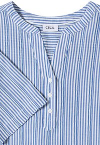 Chemise à manches longues avec rayures verticales bleues et blanches, col rond, patte de boutonnage avec trois boutons blancs et étiquette à l’intérieur du col.