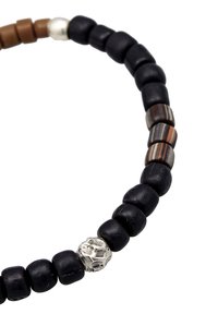 Bracelet en perles avec des perles noires, marron et rayées, mettant en valeur un détail en argent, affichant un design texturé et superposé.