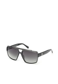 Gafas de sol con un gran marco de plástico negro angular, lentes gris degradado y brazos negros texturizados con detalles del logotipo.
