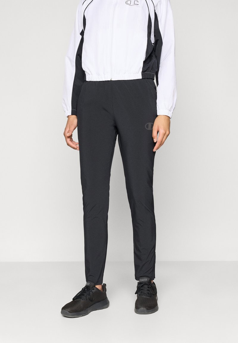 Juodi sportiniai kelnių, pritaikyti prisitaikančiam siluetui, pagaminti iš lengvos medžiagos, su elastingu juosmeniu ir nežymiu logotipo detaliu ant šlaunies.