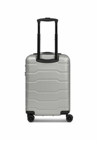 Maleta rígida plateada con superficie texturizada, ranuras horizontales, mango negro extensible y cuatro ruedas negras para movilidad.