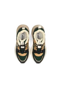 Zapatillas verdes y marrones con un interior suave, diseño de malla, acentos metálicos y suela gruesa beige. Cuerdas y plantilla de marca visibles.