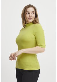 Grön ribbad topp med hög hals och korta ärmar, tillverkad av ett elastiskt material, med en figurnära design och sidoklipp för komfort.