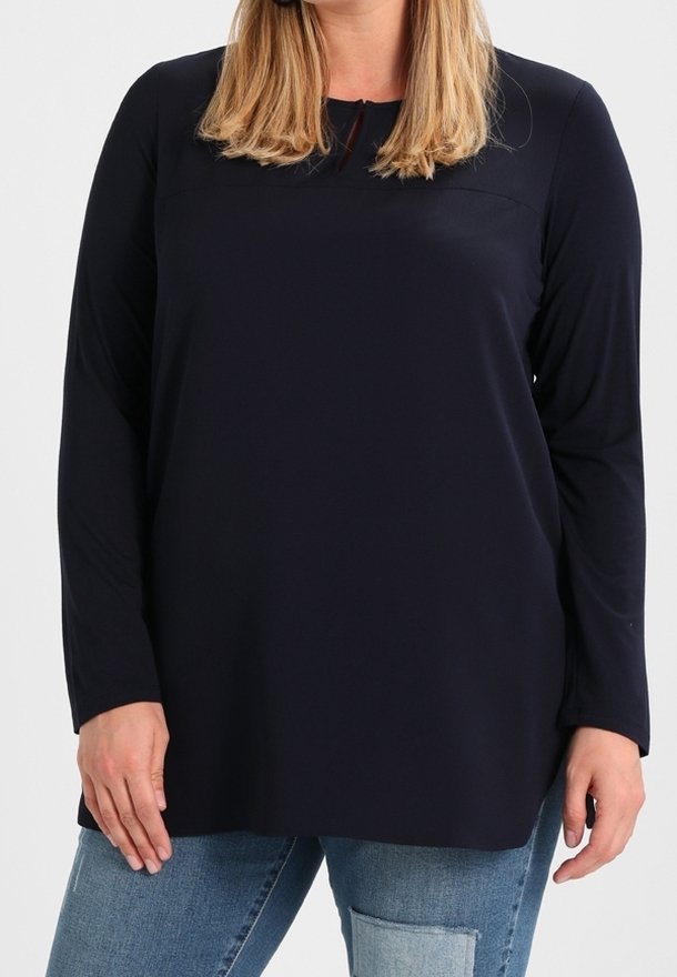 Námořnická modrá dlouhá rukávová blůza s kulatým výstřihem a mírně volným střihem. Měkká, hladká textura a minimalistický design. Sladěno s bledě modrými džíny.