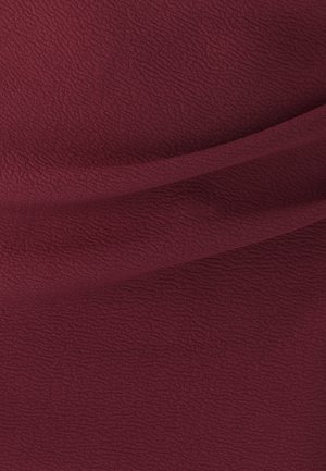 Tekstura tkanine v globoki burgundski barvi, z rahelim valovitih vzorcem in mehkim zaključkom, padajoča tako, da pokaže gube in konture.