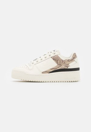 Niski kremowy sneaker z beżowym wzorem skóry węża na bocznych panelach, białymi sznurówkami i grubą kremową podeszwą na białym tle.
