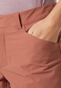 Różowe spodnie o gładkiej fakturze z haftowanymi akcentami; mają boczną kieszeń i luźny krój zaprojektowany z myślą o komforcie.